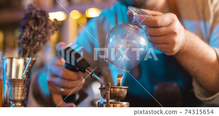 A man burning the herbs with torch burner 74315654