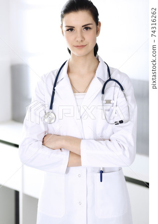 Doctor woman cheerful smiling at camera. Perfect medical service in clinic. Happy future in medicine and healthcare Doctor woman cheerful smiling at camera. Perfect medical service in clinic. Happy future in medicine and healthcare 74316262