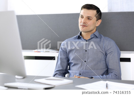 Businessman working with computer in modern office. Headshot of male entrepreneur or company director at workplace. Business concept Businessman working with computer in modern office. Headshot of male entrepreneur or company director at workplace. Business concept 74316355