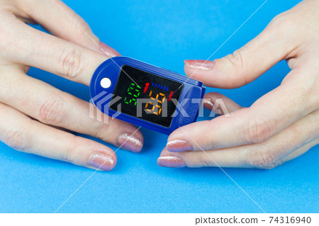Oximeter on the finger of a woman's hand, reading oxygen in human blood 74316940
