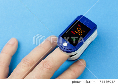 Oximeter on the finger of a man's hand on a blue background 74316942