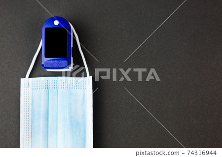 Medical mask and oximeter on a black background. Copy space 74316944