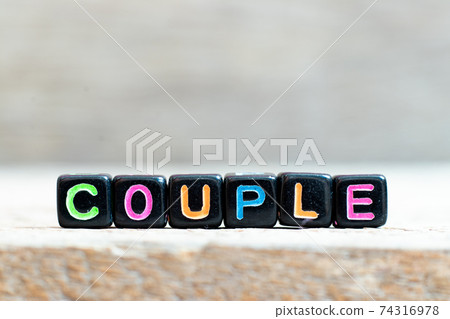 Black bead with color letter in word couple on wood background Black bead with color letter in word couple on wood background 74316978