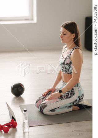 Athletic woman in sportswear does exercises at home. Woman look in tablet while diong exercises. Sport and recreation concept. Healthy lifestyle 74318098