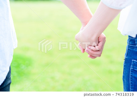 A couple of men and women holding hands on a beautiful lawn, good friends, peace A couple of men and women holding hands on a beautiful lawn, good friends, peace 74318319