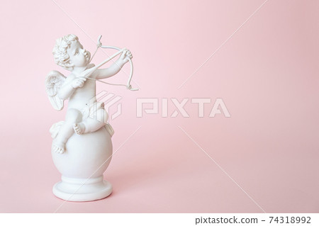 figurine of an angel Cupid with a bow on a pink background. Valentine's Day. figurine of an angel Cupid with a bow on a pink background. Valentine's Day. 74318992