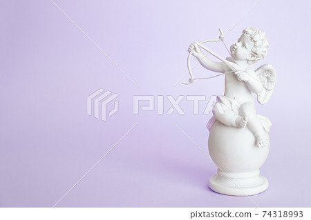 figurine of an angel Cupid with a bow on a pink background. Valentine's Day. figurine of an angel Cupid with a bow on a pink background. Valentine's Day. 74318993