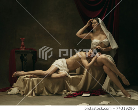 Modern remake of classical artwork - young medieval couple on dark background, comparison of eras concept Modern remake of classical artwork - young medieval couple on dark background, comparison of eras concept 74319290