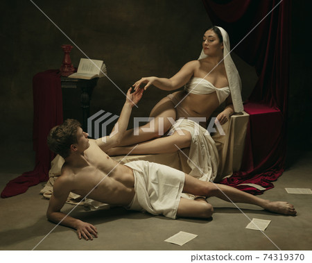 Modern remake of classical artwork - young medieval couple on dark background, comparison of eras concept Modern remake of classical artwork - young medieval couple on dark background, comparison of eras concept 74319370