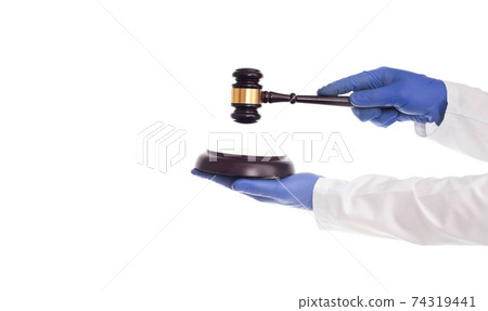 Doctor's hands hold a judicial gavel on a white background, isolate. Concept of violation of medical law, negligence of doctors Doctor's hands hold a judicial gavel on a white background, isolate. Concept of violation of medical law, negligence of doctors 74319441