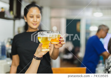 Woman hands clinking glasses of beer on family party. Woman hands clinking glasses of beer on family party. 74319505