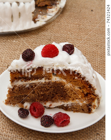 Sliced homemade biscuit cake decorated with whipped cream on plates. 74321424