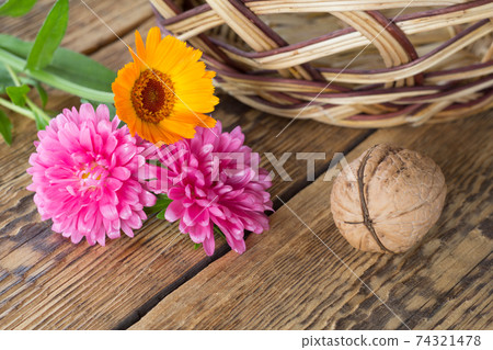Walnut and flowers over the wooden natural background. Walnut and flowers over the wooden natural background. 74321478