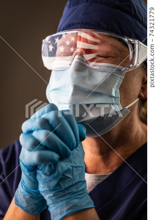American Flag Reflecting on Distressed Praying Female Medical Worker Wearing Protective Face Mask and Goggles American Flag Reflecting on Distressed Praying Female Medical Worker Wearing Protective Face Mask and Goggles 74321779