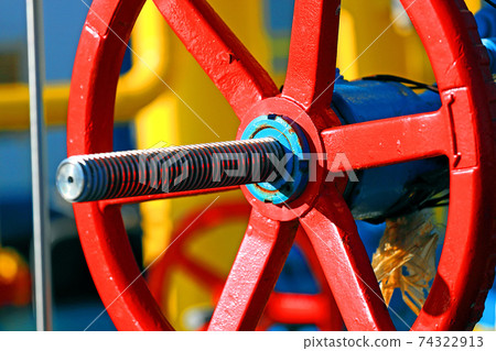 This is a red shut-off valve close-up on a sunny day in an open warehouse. Equipment for 74322913