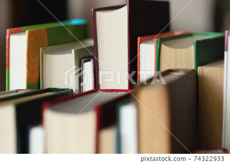 This is a lot of books standing together in several rows. Solid background of books in close-up. 74322933