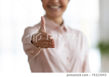 Happy female office employee giving hand for shaking 74323043