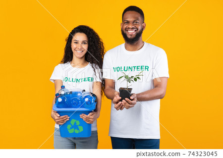 Two Multiracial Volunteers Holding Plastic Bottles And Plant, Yellow Background 74323045
