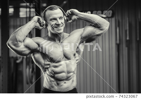 Fitness man with headphones at workout in gym Fitness man with headphones at workout in gym 74323067