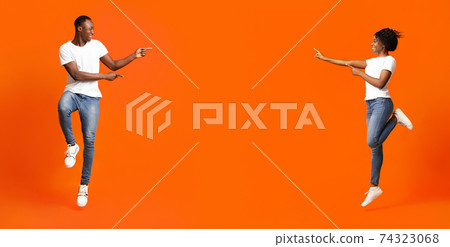 Black man and woman pointing at empty space between them Black man and woman pointing at empty space between them 74323068