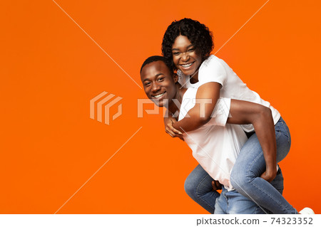 Funny black lovers posing on orange studio background 74323352