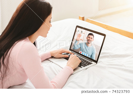Online communication during coronavirus lockdown. Young woman making video call, speaking with her boyfriend on laptop 74323793
