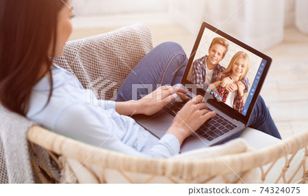 Young mother with laptop talking to her kids online, having video chat with cute boy and girl on webcam 74324075