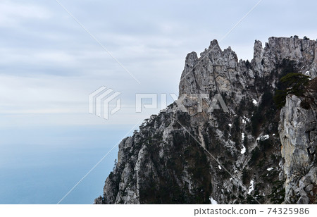 sheer cliffs with sparse trees and patches of snow over the winter sea sheer cliffs with sparse trees and patches of snow over the winter sea 74325986