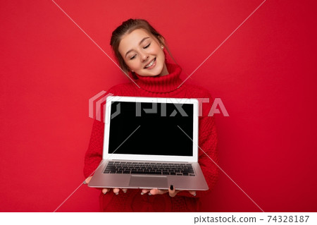 Photo of Beautiful satisfied happy young woman holding computer laptop looking down at netbook 74328187