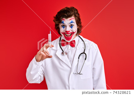 male clown pediatrician prepared a syringe isolated over red background 74328621