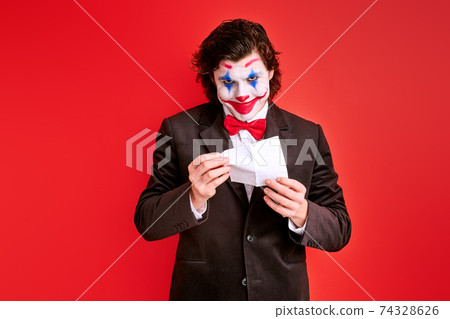 handsome male magician performing a trick with hands isolated on red background 74328626