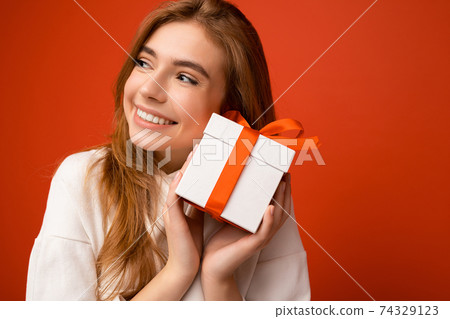 Closeup portrait photo of beautiful happy blonde young female person isolated over orange background Closeup portrait photo of beautiful happy blonde young female person isolated over orange background 74329123