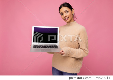 beautiful smiling young woman with dark hair looking at camera holding computer laptop with empty 74329214