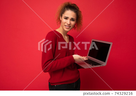 Close-up portrait of beautiful amazed surprised astonished dark blond woman holding laptop computer 74329216