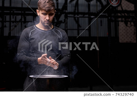 caucasian young athlete getting ready for weight lifting training, use talc caucasian young athlete getting ready for weight lifting training, use talc 74329740