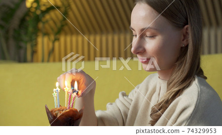 Woman lights a candle on a delicious cake Woman lights a candle on a delicious cake 74329953