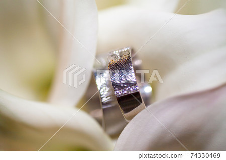 Close view on calla flowers with wedding rings in warm colors Close view on calla flowers with wedding rings in warm colors 74330469