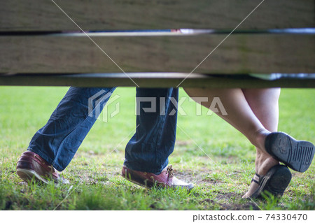 A young couple in love is sitting on a bench in the park A young couple in love is sitting on a bench in the park 74330470