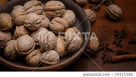 Nuts. whole walnuts in an earthenware dish on a dark wooden table.  74331380