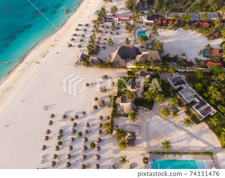 Aerial view of Thatched Roof Umbrellas Pattern on Wide Coastal line of White Sand of Kendwa Beach in Kendwa village, Zanzibar 74331476