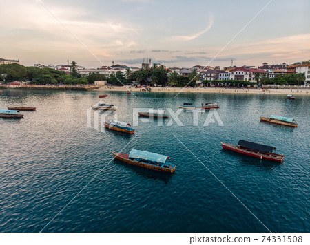 Aerial. Stone town, Zanzibar, Tanzania. Flock of Show Ships near the Zanzibar Coastline in Stone Town on Blue Transparent Water Aerial. Stone town, Zanzibar, Tanzania. Flock of Show Ships near the Zanzibar Coastline in Stone Town on Blue Transparent Water 74331508