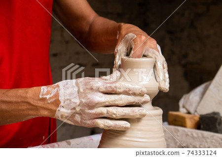 Man making ceramic articles on the pottery wheel in a traditional factory in the city of Raquira located in the department of Cundinamarca in Colombia Man making ceramic articles on the pottery wheel in a traditional factory in the city of Raquira located in the department of Cundinamarca in Colombia 74333124