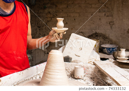 Man making ceramic articles on the pottery wheel in a traditional factory in the city of Raquira located in the department of Cundinamarca in Colombia Man making ceramic articles on the pottery wheel in a traditional factory in the city of Raquira located in the department of Cundinamarca in Colombia 74333132
