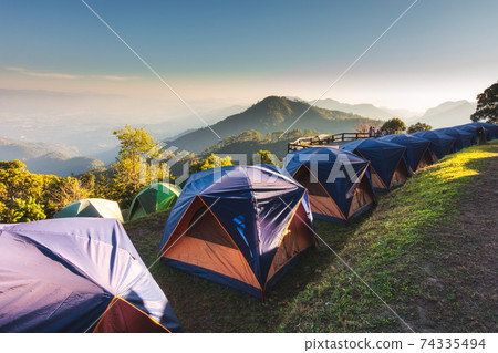 Tourist Camp Tent and Terrace Under Pine Trees Forest During Sunrise, Field Campground for Camping Vacation Adventure Outdoors and Leisure Activity. Backpacking Tourism, Travel Adventures Lifestyles Tourist Camp Tent and Terrace Under Pine Trees Forest During Sunrise, Field Campground for Camping Vacation Adventure Outdoors and Leisure Activity. Backpacking Tourism, Travel Adventures Lifestyles 74335494