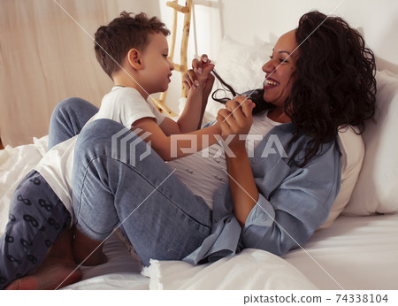 young pretty african americam mother with son in bed at morning playing, happy family, lifestyle people concept young pretty african americam mother with son in bed at morning playing, happy family, lifestyle people concept 74338104