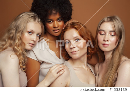 young pretty caucasian, afro, scandinavian woman posing cheerful together on brown background, lifestyle diverse nationality people concept 74338189