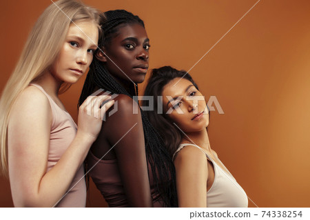 young pretty asian, caucasian, afro woman posing cheerful together on brown background, lifestyle diverse nationality people concept 74338254