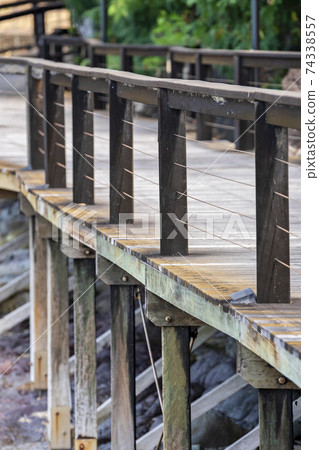 A timber walkway built on tall posts along a coastal tourist attraction 74338557