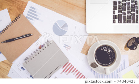 Top view Office desk with laptop,supplies and hot coffee,graph paper Top view Office desk with laptop,supplies and hot coffee,graph paper 74340425