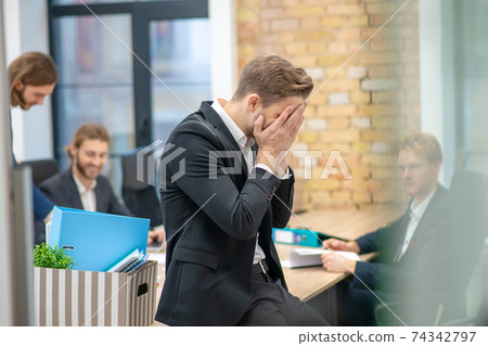 Man covering his face with hands sitting in office Man covering his face with hands sitting in office 74342797